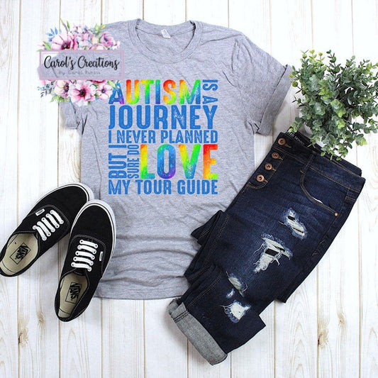 Gray t-shirt with colorful text, black sneakers, and distressed jeans on a wooden surface.