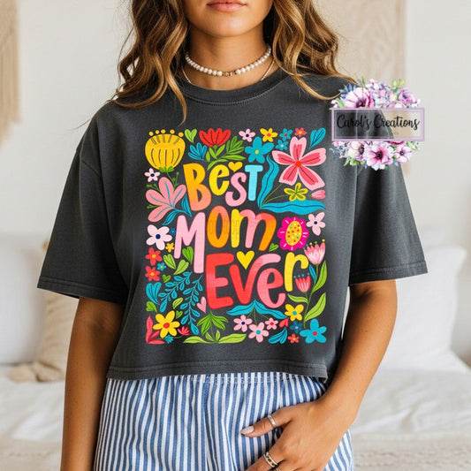 Person wearing a black t-shirt with colorful 'Best Mom Ever' design.