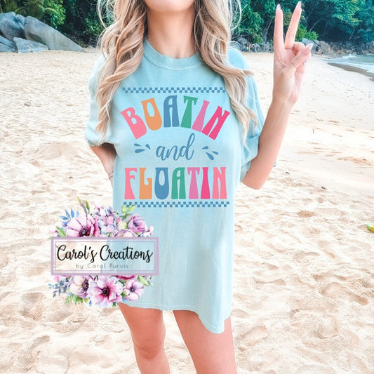Woman wearing a light blue t-shirt with colorful text on a beach, featuring 'Carol's Creations' logo.