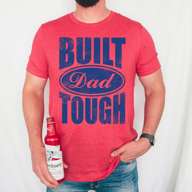 Person wearing a red t-shirt with 'Built Dad Tough' text, holding a bottle.