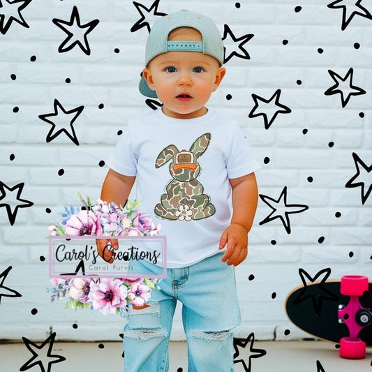 Child wearing a white t-shirt with a graphic design, standing against a wall with star patterns and 'Carol's Creations' branding.