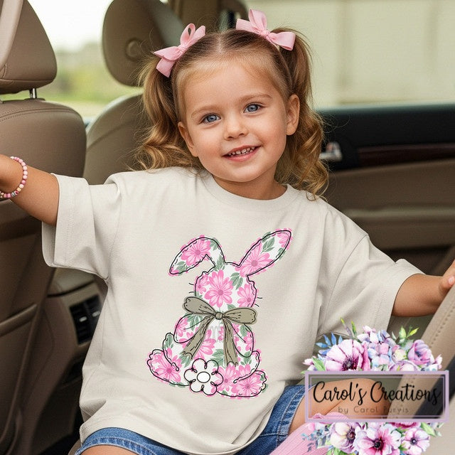 Child wearing a t-shirt with a floral bunny design, sitting in a car.