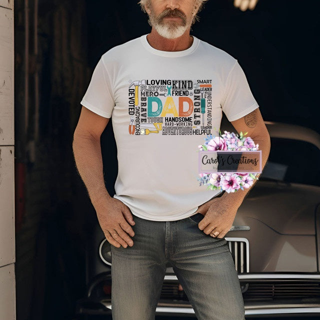 Man wearing a white t-shirt with colorful text design, standing in front of a car.