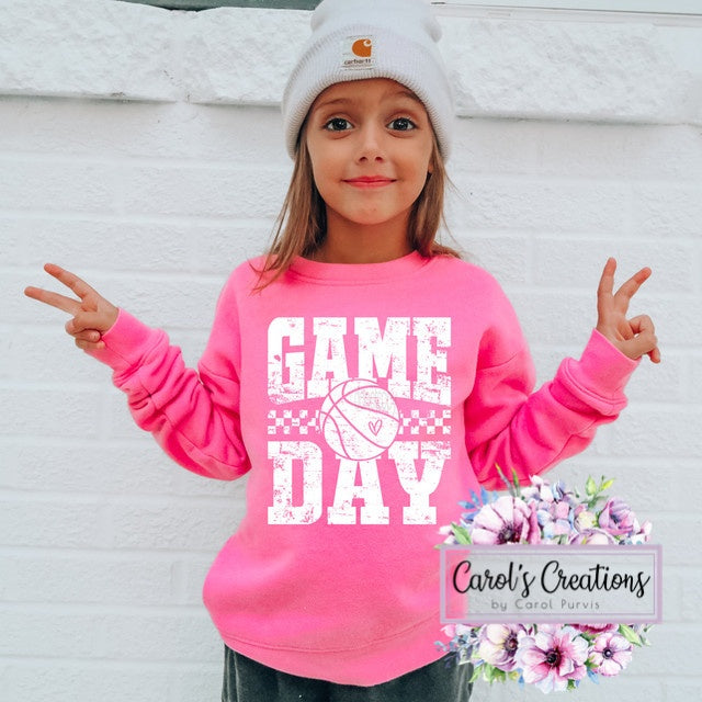 Child wearing a pink 'Game Day' sweatshirt with a white beanie, standing against a light background.