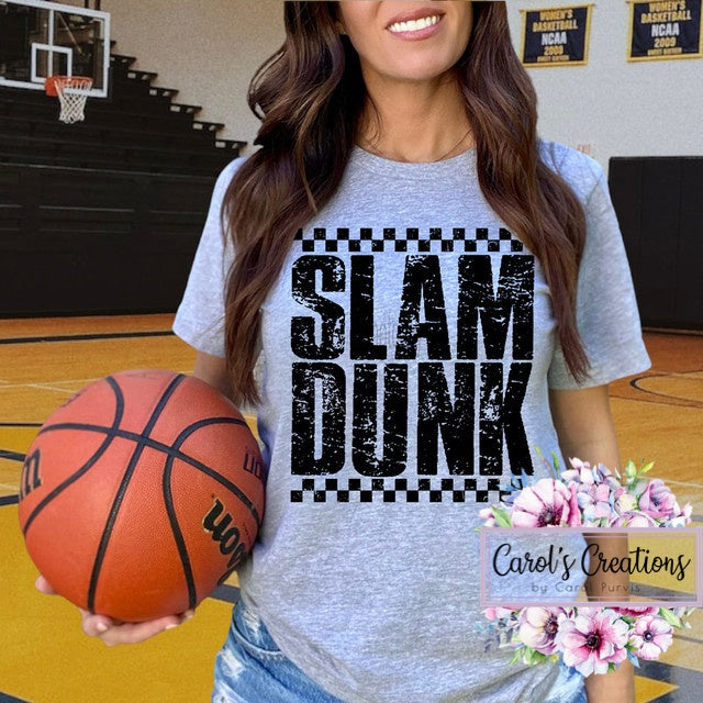 Person wearing a 'SLAM DUNK' t-shirt holding a basketball on a gymnasium floor.