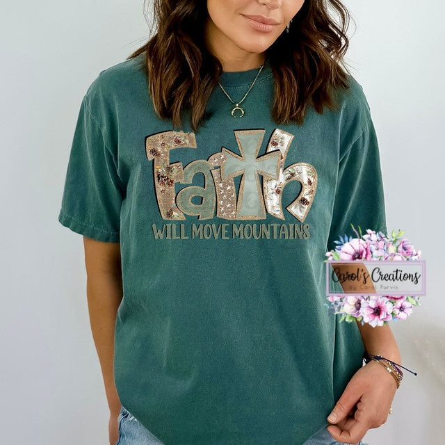 Person wearing a teal t-shirt with 'Faith Will Move Mountains' text, standing against a plain background.