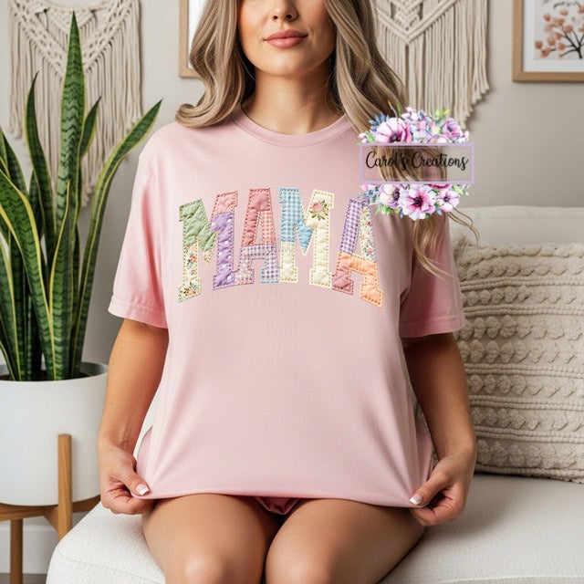 Woman wearing a pink 'MAMA' shirt with colorful letters in a home setting.