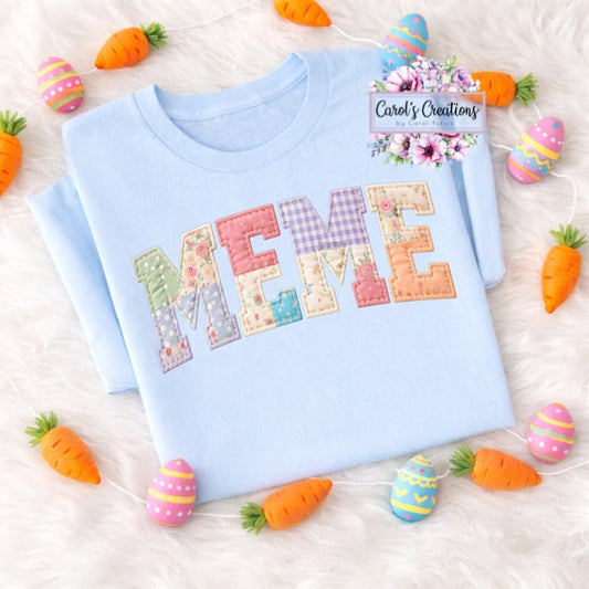 Light blue sweatshirt with colorful 'MEME' design on a white surface with Easter decorations.