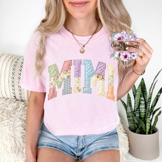 Person wearing a pink t-shirt with colorful 'MOM' design, holding a card with 'Carole's Creations' branding.