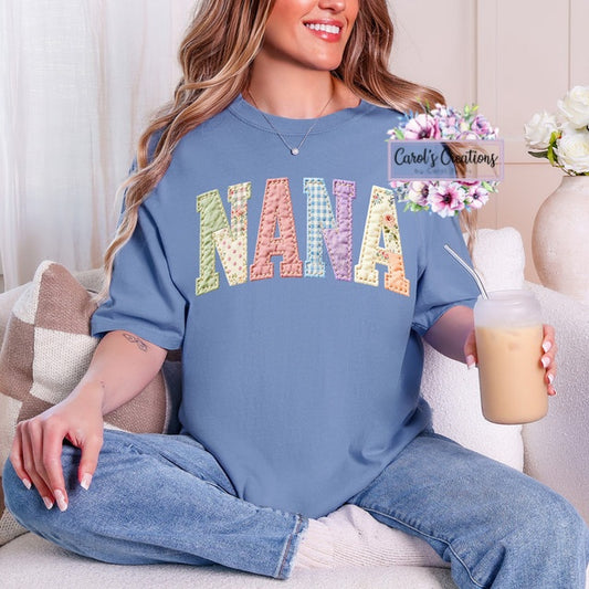 Woman wearing a blue shirt with 'NANA' in colorful letters, sitting on a couch holding a drink.