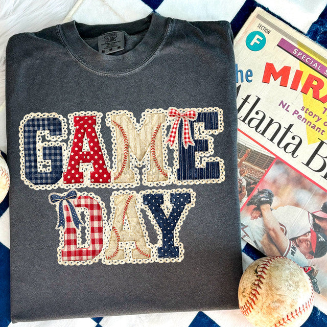Gray sweatshirt with 'GAME DAY' text in baseball-themed graphics on a sports-themed magazine background.
