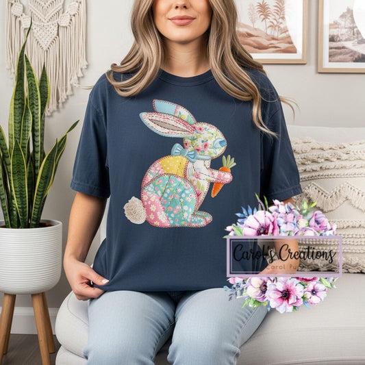 Woman wearing a navy blue t-shirt with a floral bunny design, sitting on a couch in a home setting.