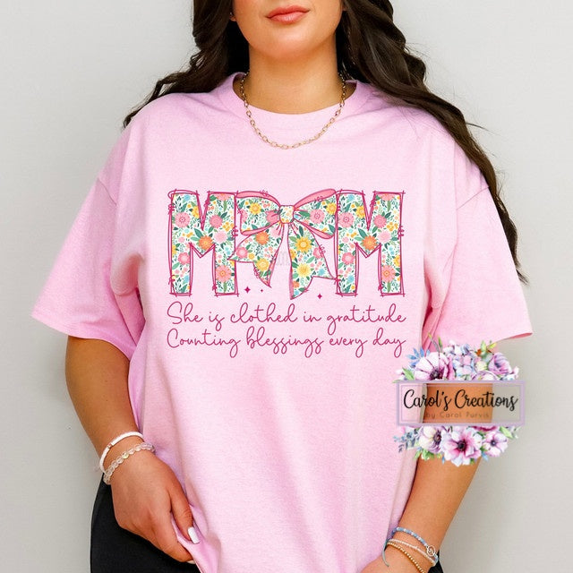 Person wearing a pink t-shirt with floral text design and branding at the bottom.