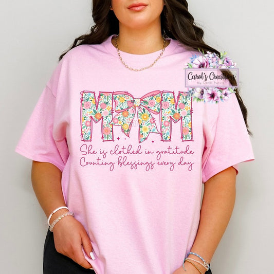 Person wearing a pink t-shirt with floral 'MAMA' design and text.