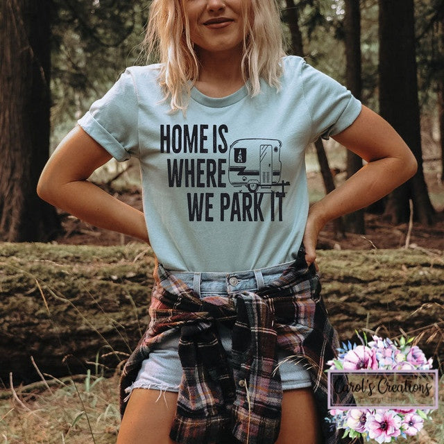 Person wearing a t-shirt with 'Home is where we park it' design in a forest setting