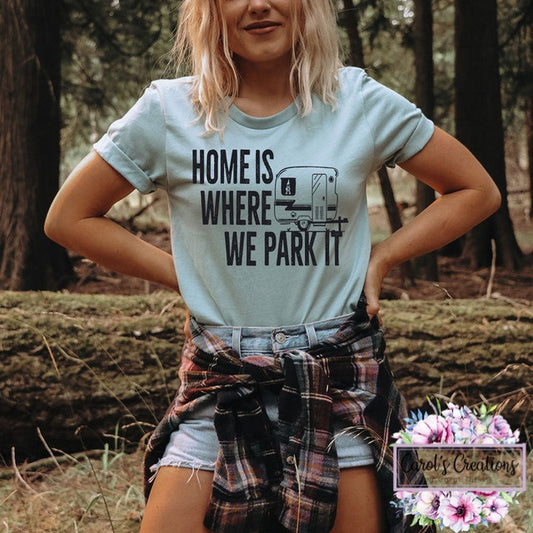 Person wearing a t-shirt with 'Home is where we park it' design in a forest setting