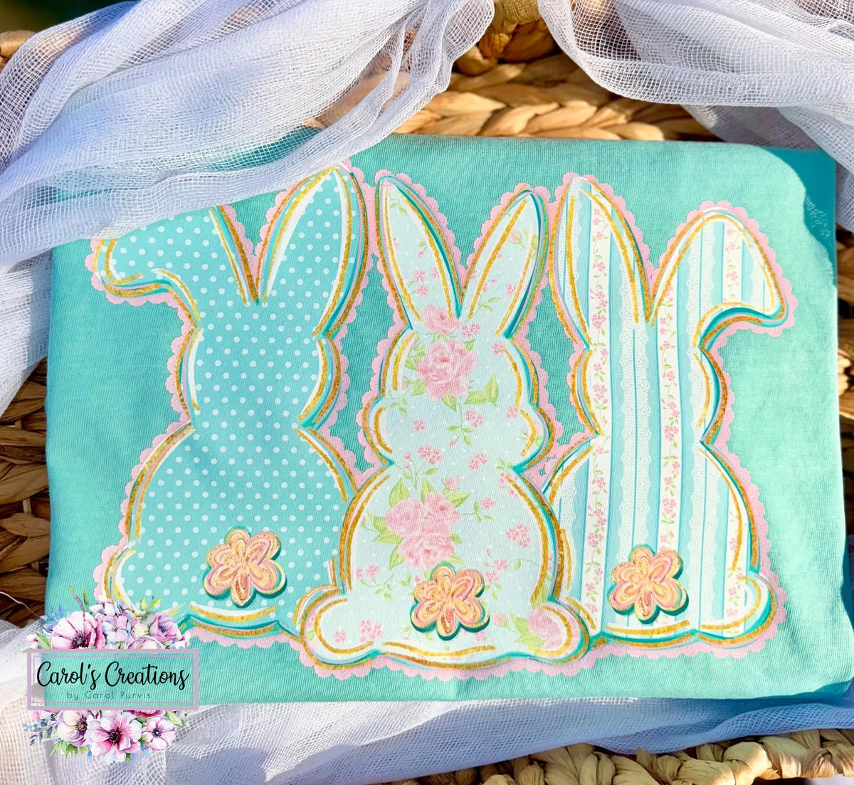 Fabric with bunny designs on a teal background, featuring floral elements, on a woven surface.