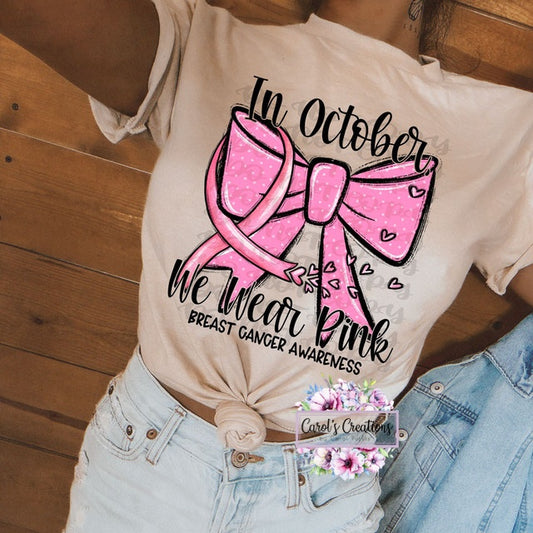 Beige t-shirt with pink ribbon and text for breast cancer awareness, worn by a person.