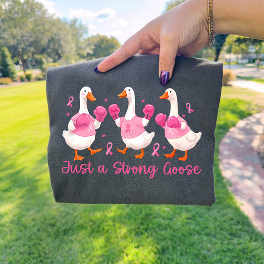 Gray pouch with cartoon ducks and 'Just a Strong Goose' text held by a hand outdoors.