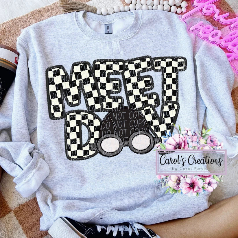 Gray sweatshirt with checkered text design on a surface with decorative items.