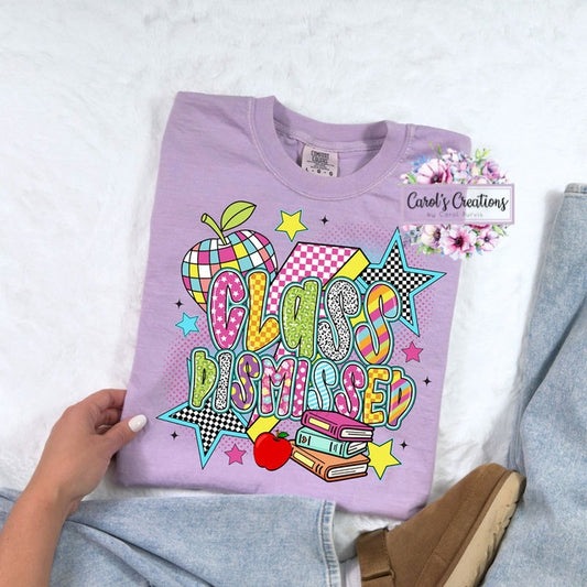 Purple t-shirt with colorful 'Class Dismissed' design held by a person on a light background