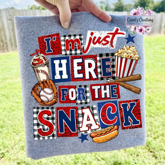 Textile with colorful graphics and text 'I'm just here for the snack' held outdoors.