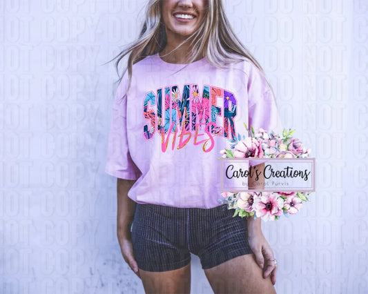 Woman wearing a pink 'Summer Vibes' shirt with floral graphics, standing against a light blue textured background.