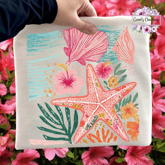 Hand holding a tote bag with a colorful starfish design surrounded by pink flowers.