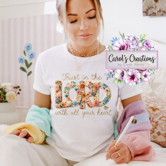 Woman wearing a white t-shirt with colorful text and flowers, sitting on a couch.