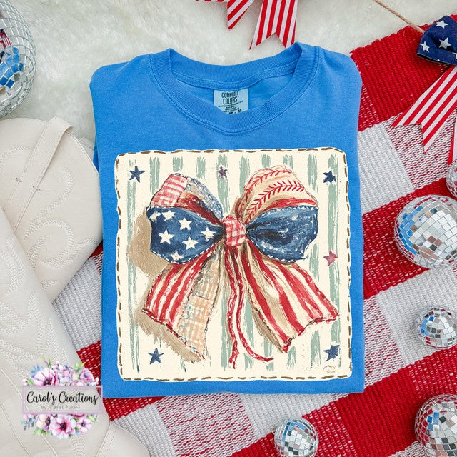 Blue t-shirt with a decorative bow design featuring American flag colors on a textured surface.