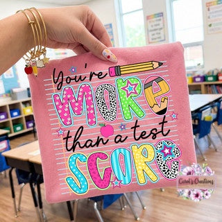 Pink notebook with colorful text held by a hand in a classroom setting